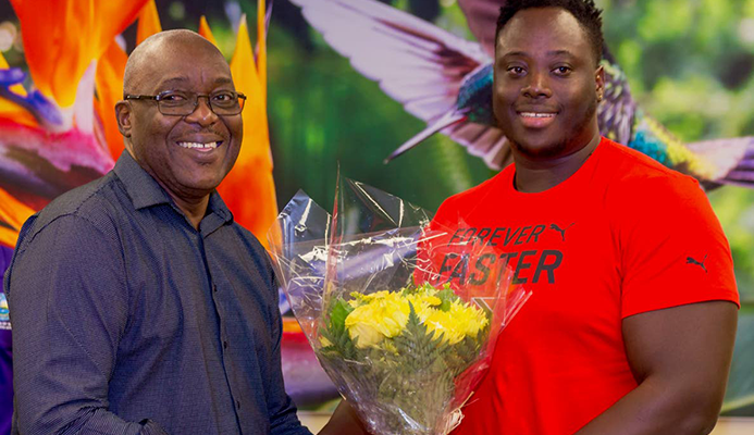 Chief Secretary Kelvin Charles presents 2019 Parapan Am double medallist Akeem Stewart with a bouquet of flowers at a ceremony to welcome him home on Tuesday at the ANR Robinson International Airport.