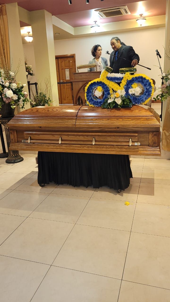 The casket bearing the body of the late Terence Chapman is seen here with a wreath designed as a bike on top of it for the funeral service at the First Church of the Open Bible in San Fernando. Chapman was later cremated. (Image obtained at guardian.co.tt)